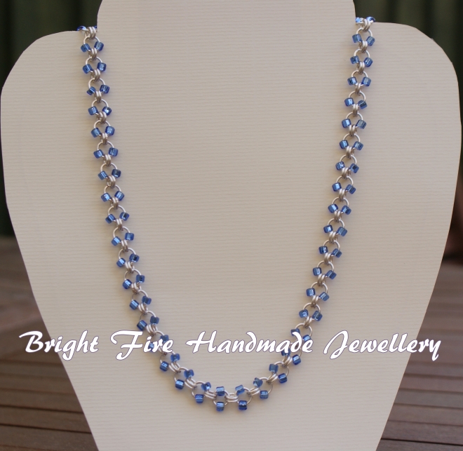 Handmade linked necklace, silver-plated with blue beads.